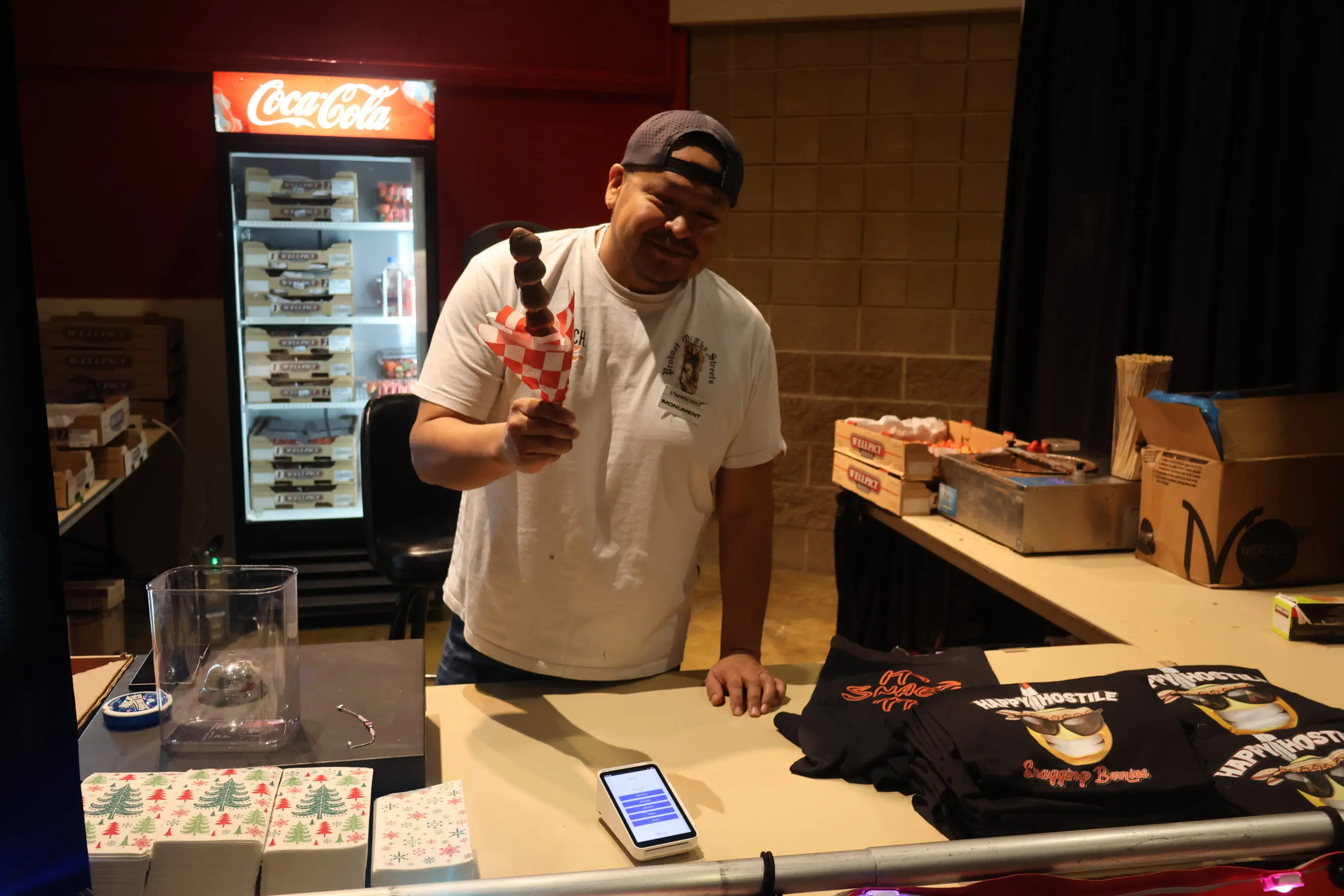 Vender holding a stick of chocolate covered strawberries