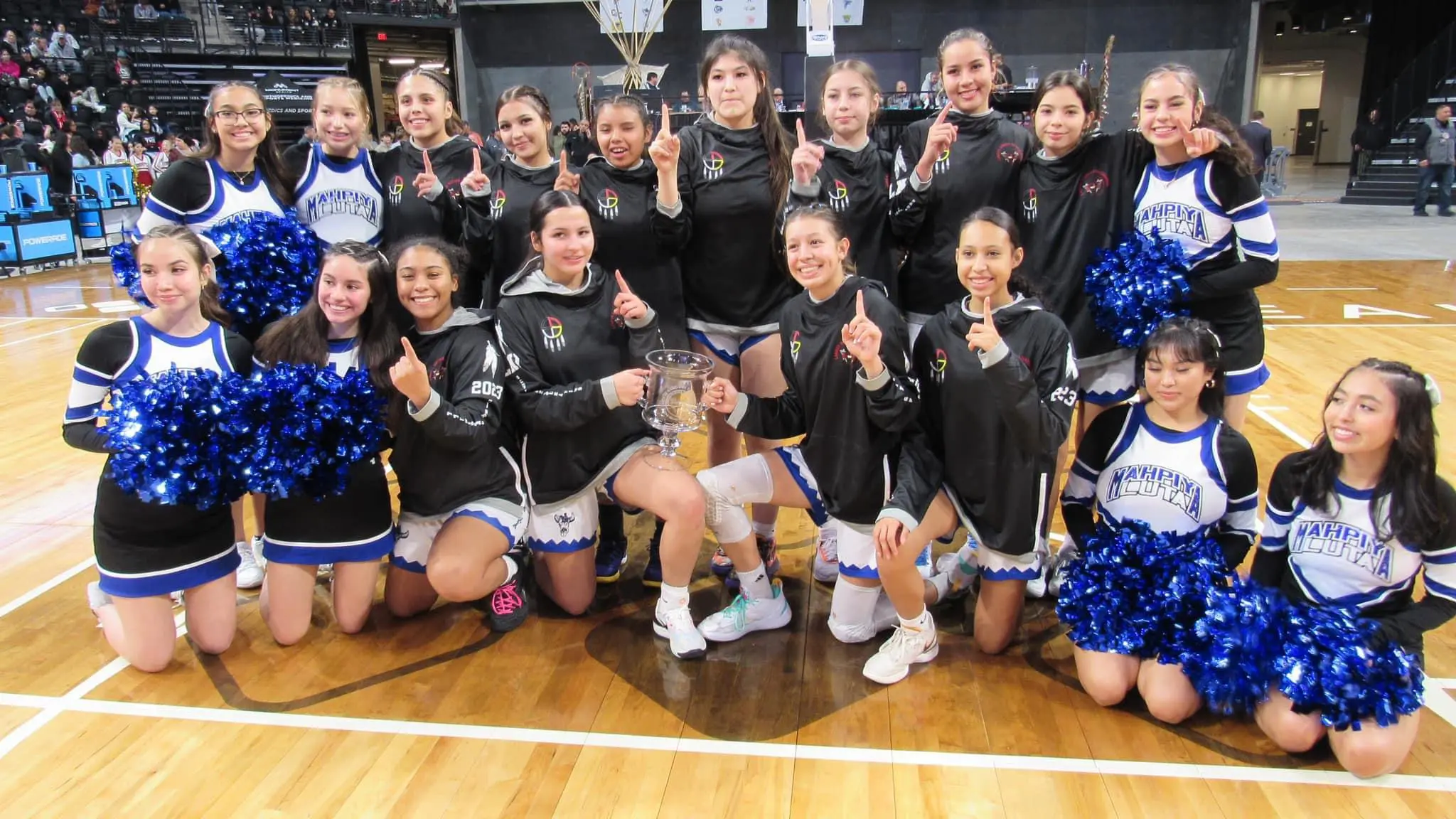 Cheerleaders and athletes holding a trophy